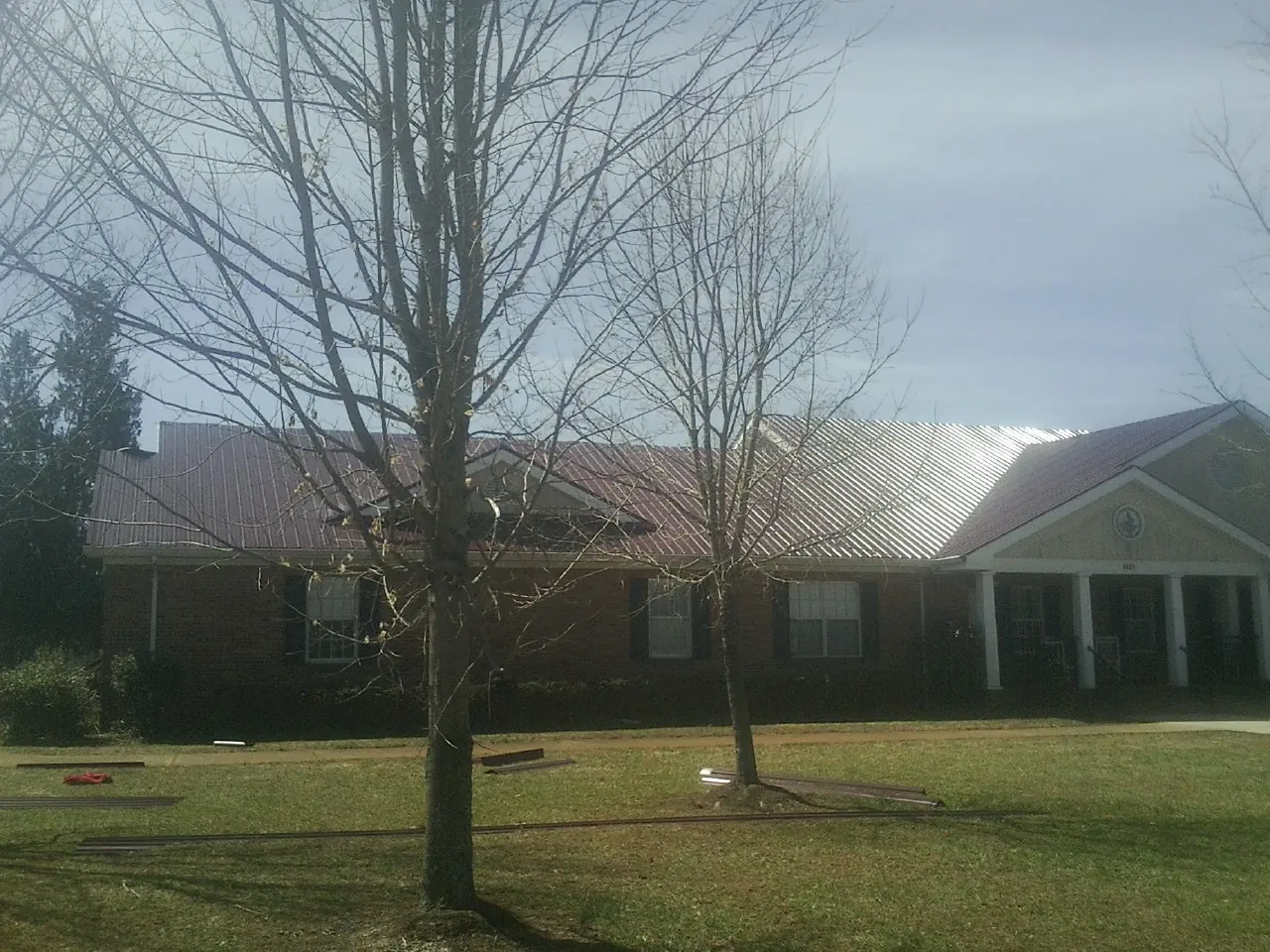 Red metal roof on a brick building seen from the front lawn in Norman