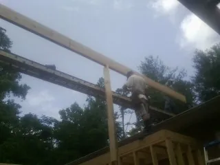Carpenter setting a ridge beam over a new addition frame — Ice Dam Removal by Roofing Brothers in Norman