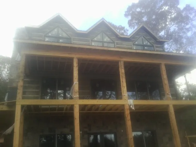 Dormers and porch framing on a large log home under construction — Roof Coating work by our crew in Norman
