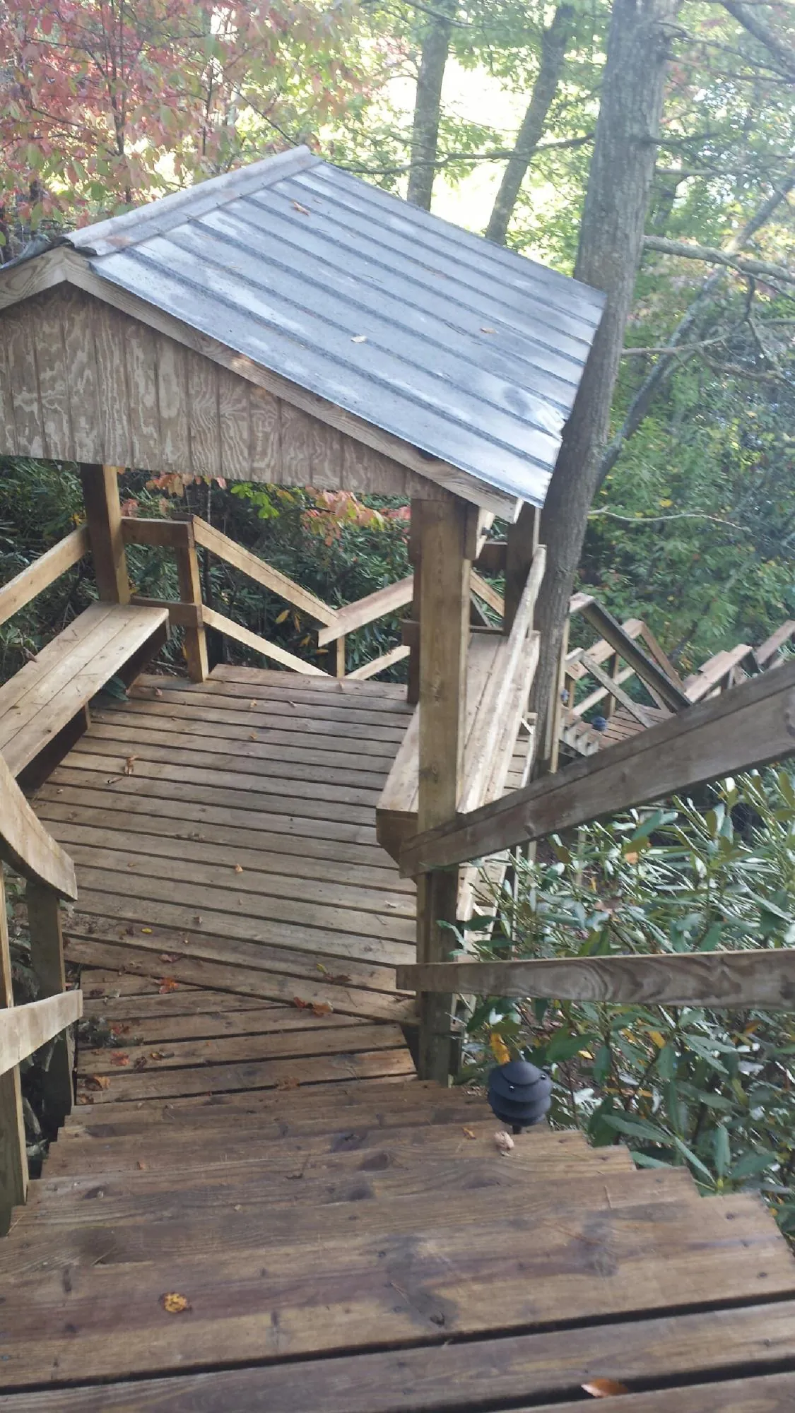 Metal roofed shelter over wooden steps on a wooded walkway — Skylight Repair & Installation work by our crew in Norman