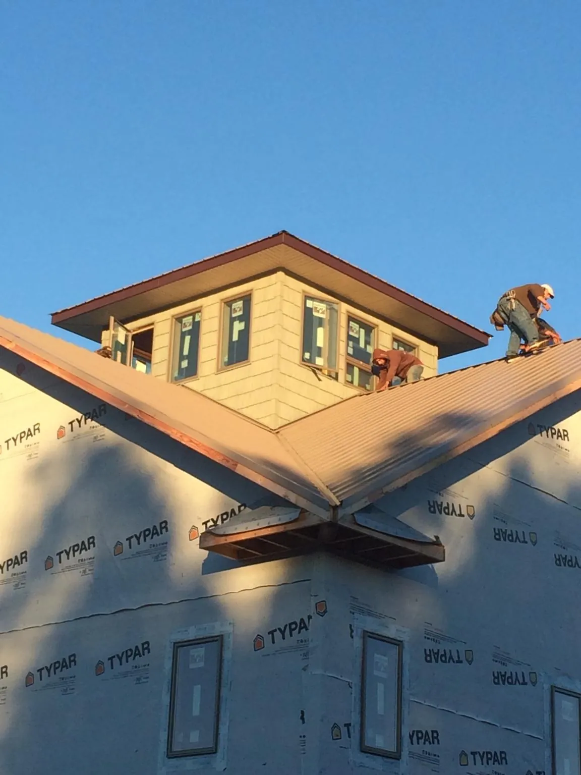 Roofers working around a rooftop cupola on a new metal roof at sunset — Roof Waterproofing in Norman by Roofing Brothers